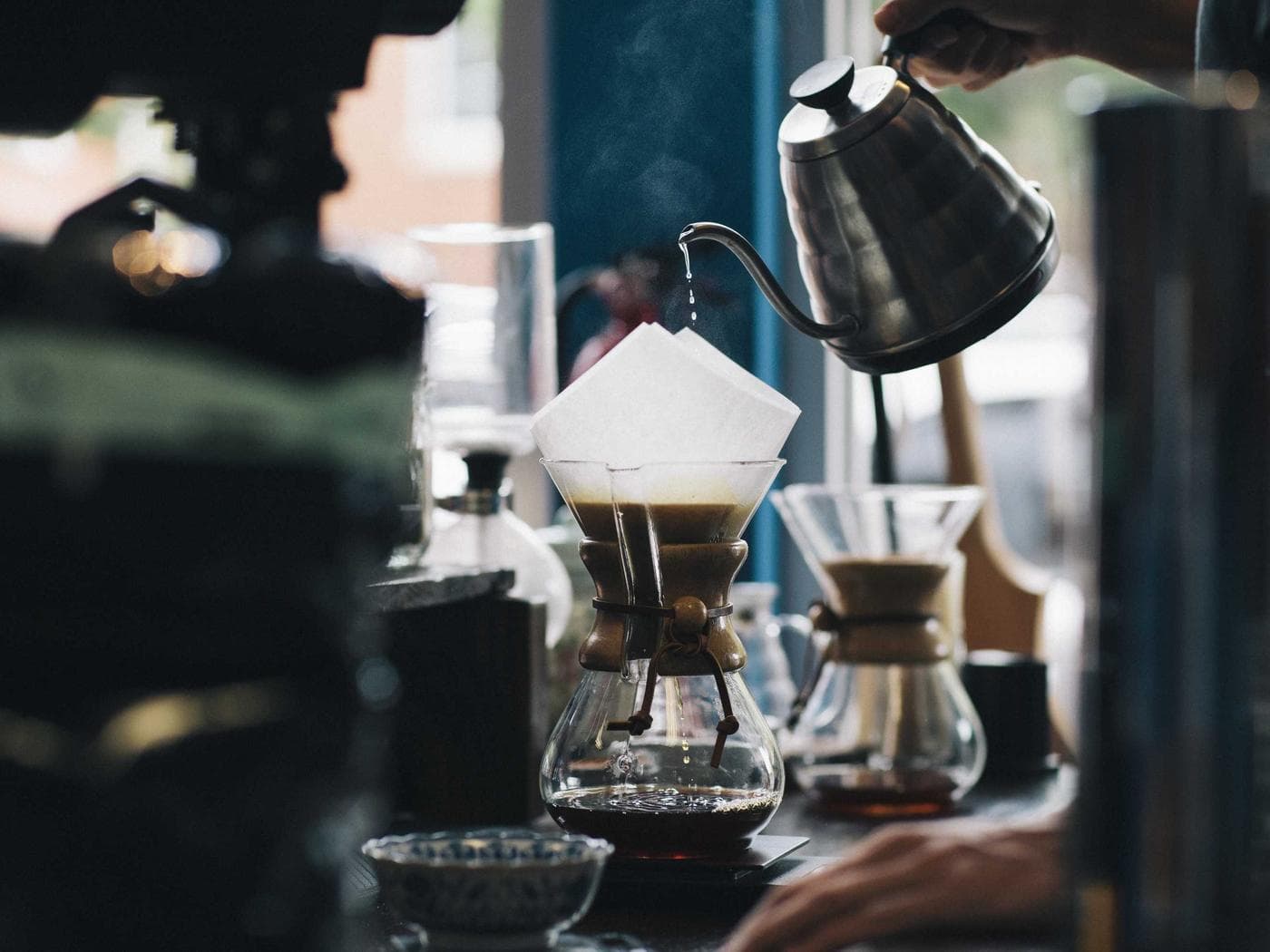 A barista making pour-over coffee behind the counter