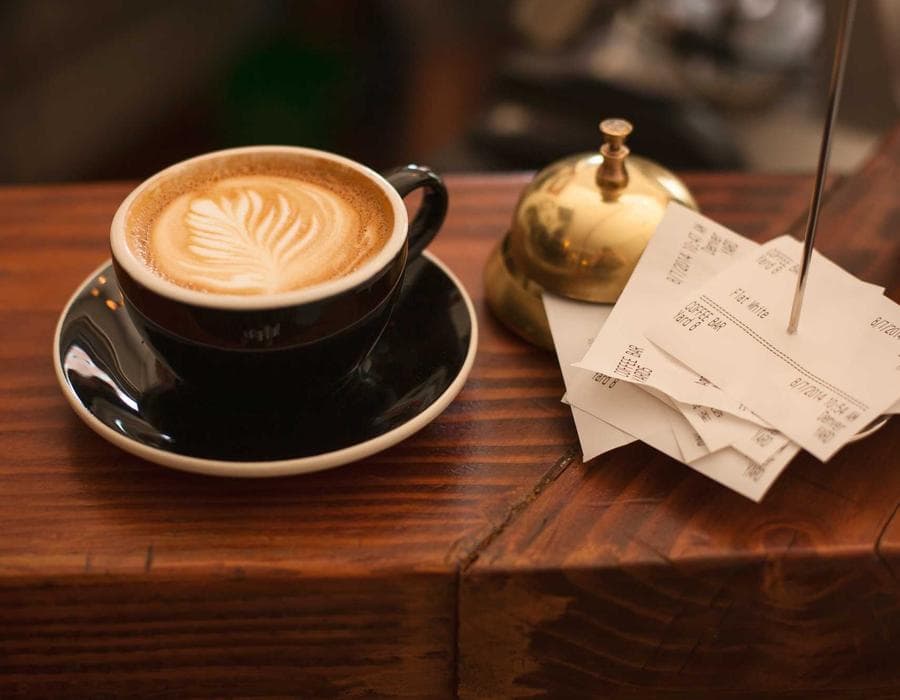 A latte served next to order tickets on the counter